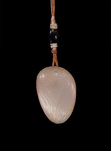 Nephrite pendant, pale grey with light brown russet areas carved as cicada gripping a pea pod with leaves.