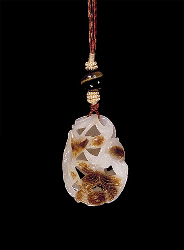 Nephrite pendant, pebble of white colour with a darker brown leathery coloured skin, the body all pierced and carved with an aquatic scene showing a fan-tailed carp with lotus, and a crab and leaves.