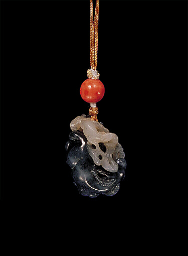 Reverse: Nephrite pendant, dark grey mottled with mutton fat and lighter grey areas, carved in the form of a large, reclining ram, with two other baby rams by the side, one in black.