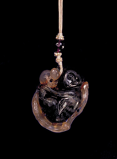 Chalcedony pendant, pale beige and brown agate with a much darker brown area carved as a large monkey holding peaches amongst ruyi fungus.