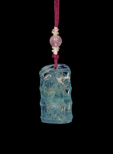 Glass pendant of pale translucent blue, suffused throughout with lighter creamier areas in imitation of aquamarine, the body carved as a section of bamboo with leaves.